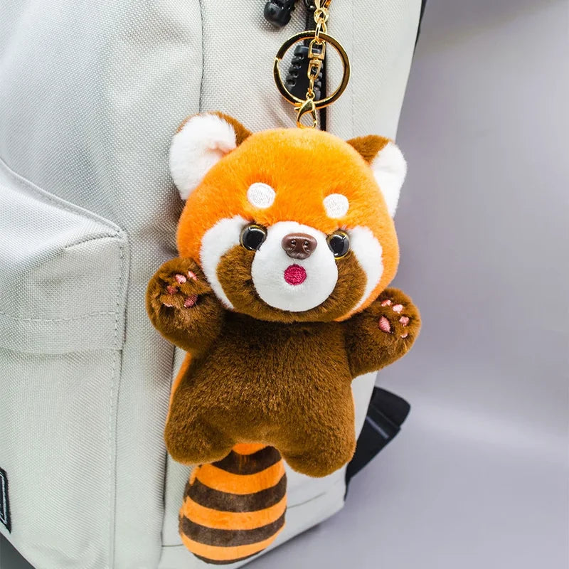 Mini peluche panda roux sur un sac a dos
