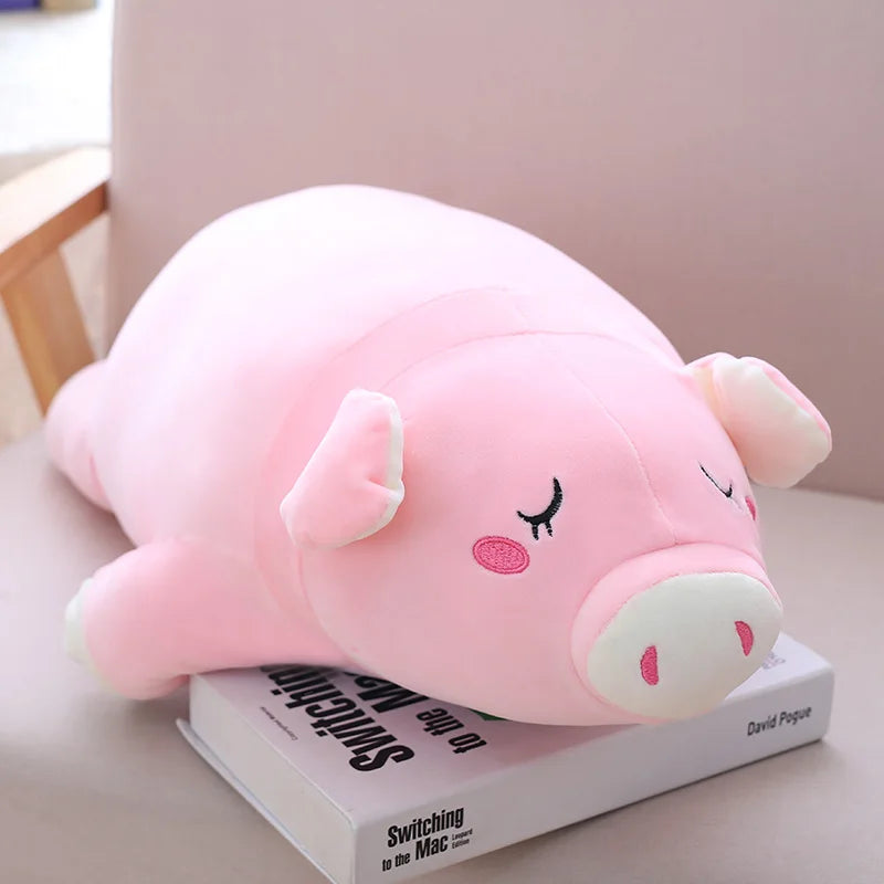 Peluche cochon rose endormi sur un livre