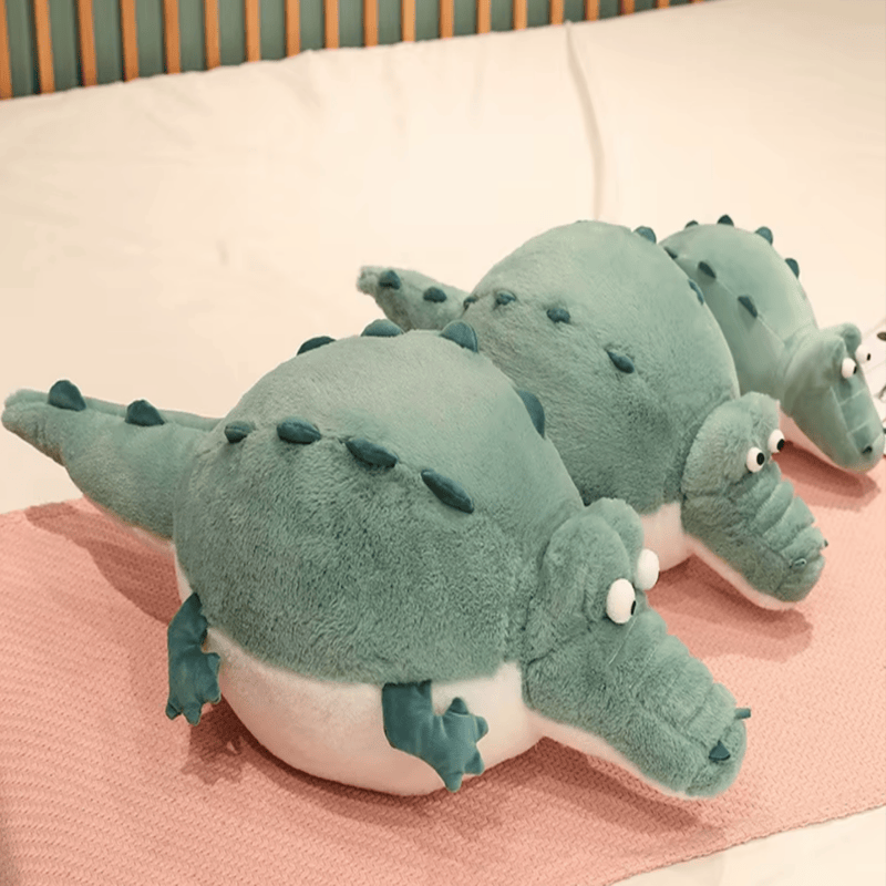 Trois peluches crocodiles cartoon sur un lit
