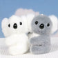 Deux mini peluches koala blanc et gris sur un drap