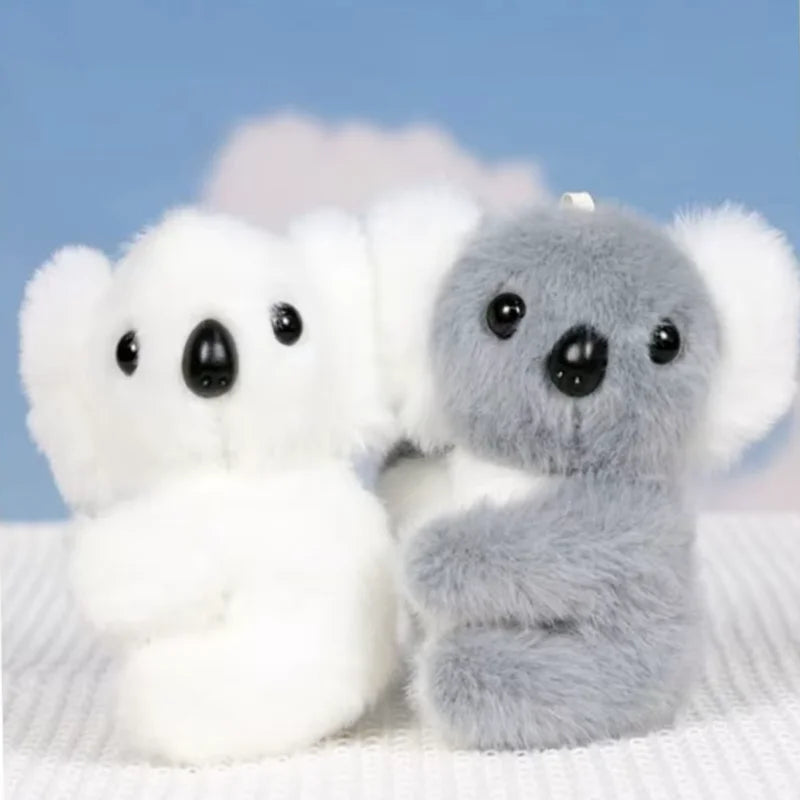Deux mini peluches koala blanc et gris sur un drap