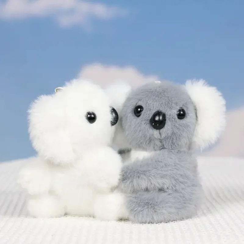 Deux mini peluches koala blanc et gris sur un drap dont un qui tourne la tête
