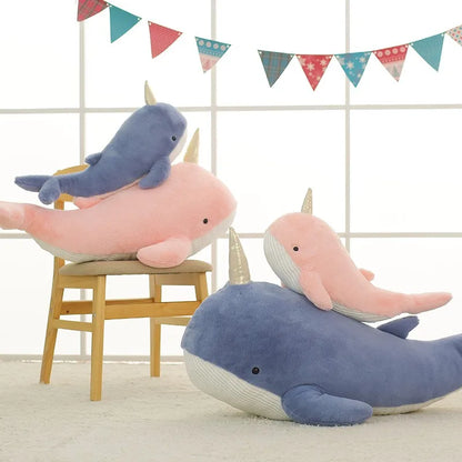 Quatre peluches baleines licorne sur un tapis et sur une chaise