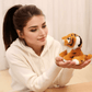 Peluche bébé tigre orange assis sur la main d'une fille
