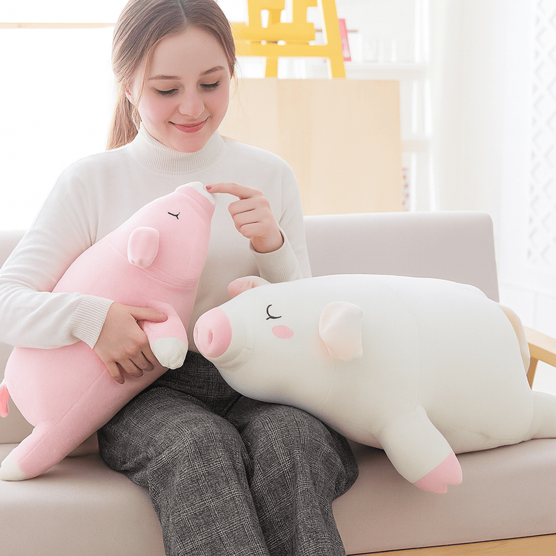Deux peluches cochons endormies sur une fille, sur un canapé