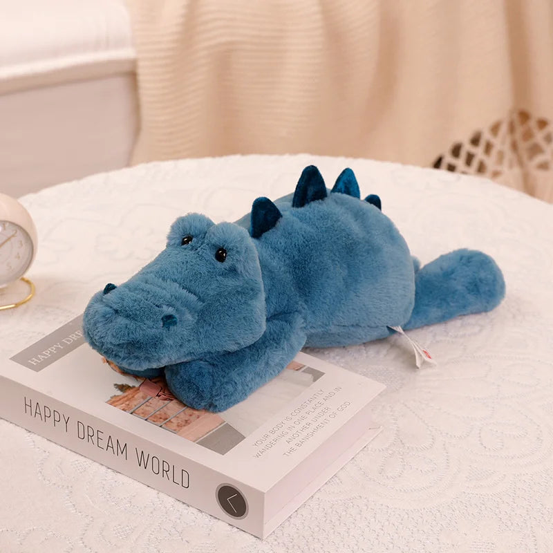 Peluche crocodile bleu couché sur un livre 