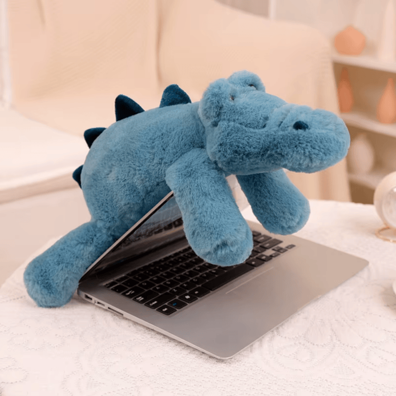 Peluche crocodile bleu posé sur un macbook pro