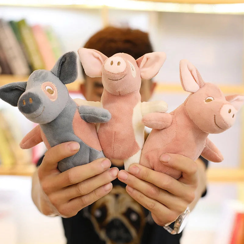 Trois peluches des petits cochons dans les mains d'un petit garçon