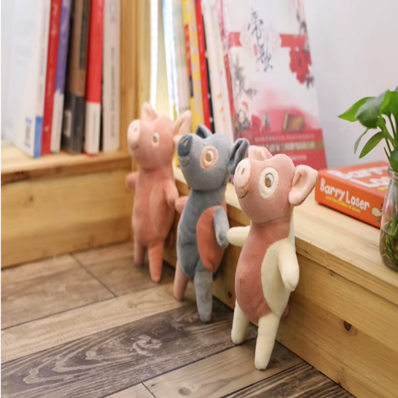 Trois peluches des petits cochons devant une bibliothèque