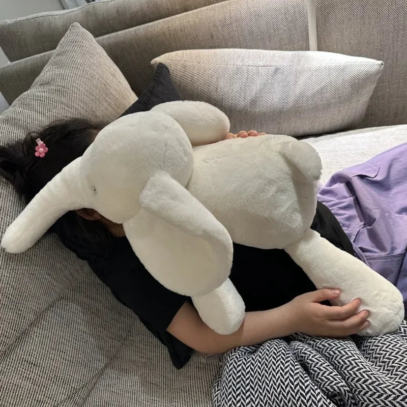 Peluche éléphant blanche super douce posée sur une fille sur un canapé