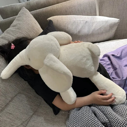 Peluche éléphant blanche super douce posée sur une fille sur un canapé