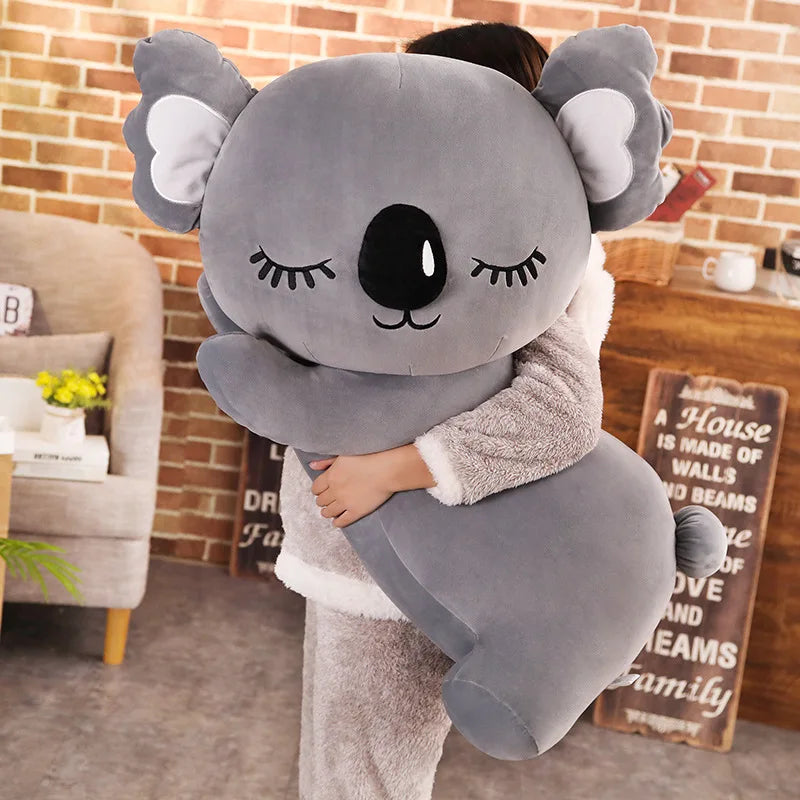 Peluche koala gris endormi dans les bras d'une fille