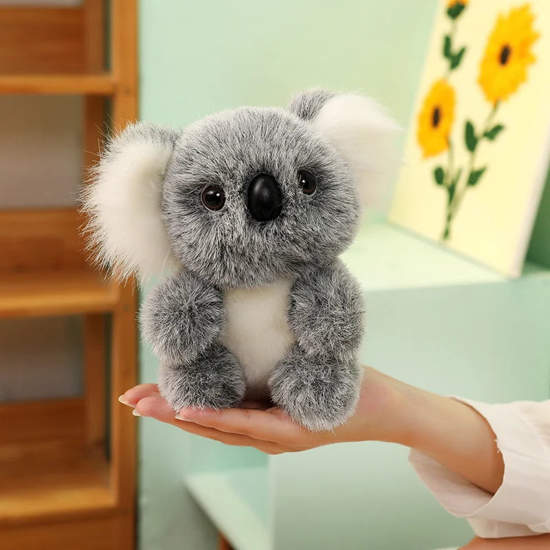 Peluche koala gris grande famille dans la main d'une femme