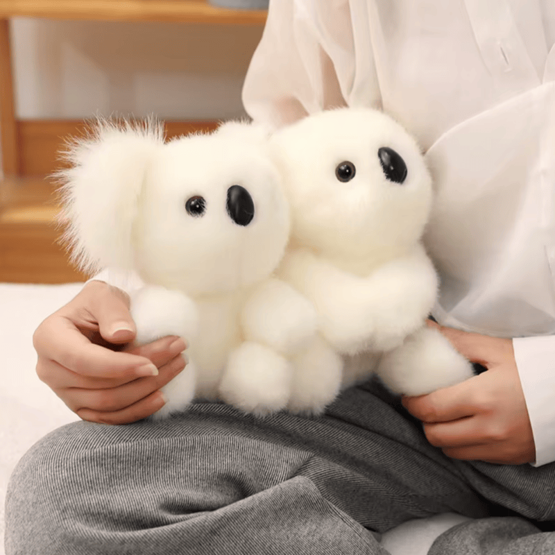 Peluche koala gris grande famille sur la cuisse d'une femme