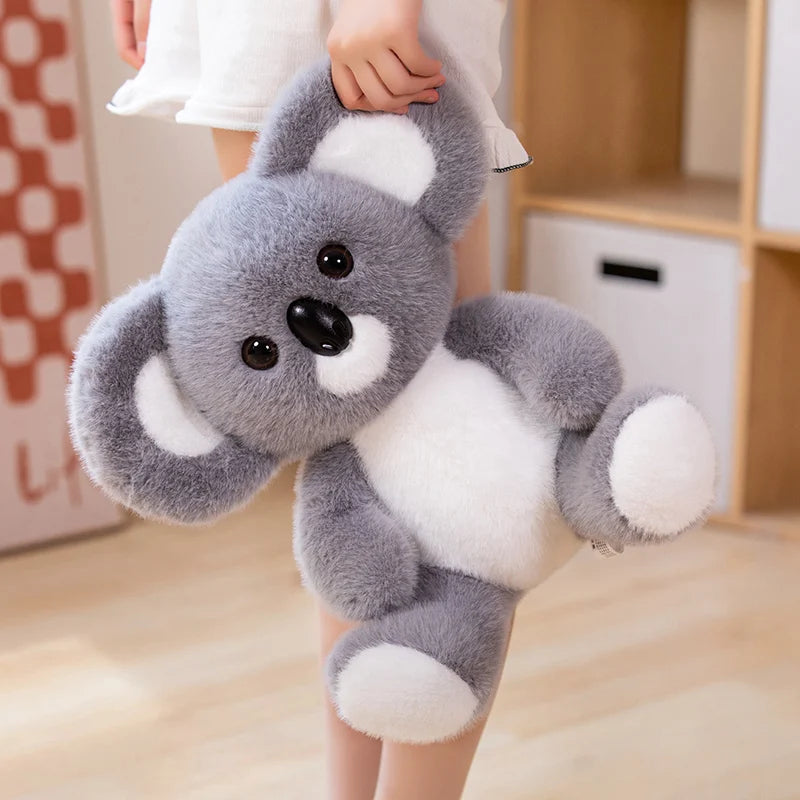 Peluche koala mignonne tenue par l'oreille d'une fille