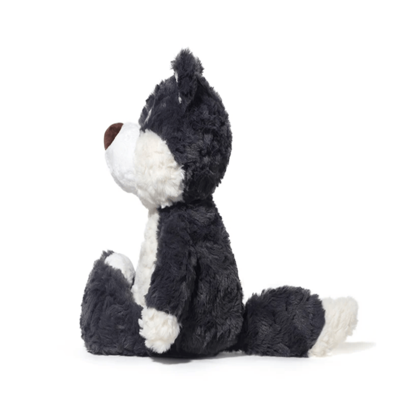 Peluche loup gris foncé assis de côté sur fond blanc