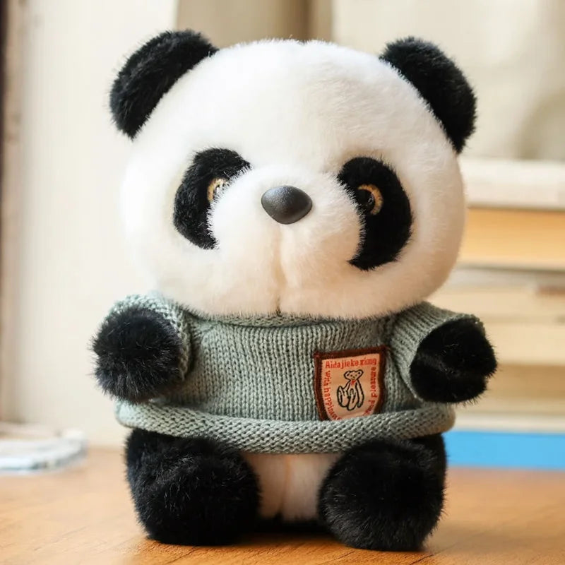 Peluche panda avec son pull gris sur un bureau