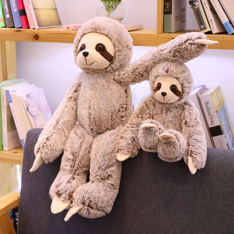 Deux peluches paresseux assis sur un rebord d'un canapé