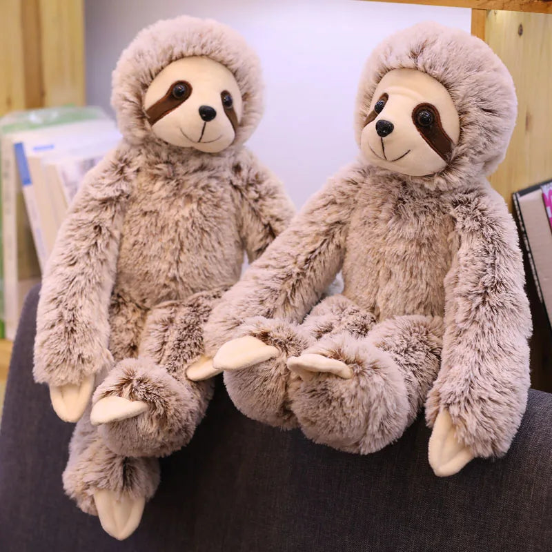 Deux peluches paresseux assis sur un rebord d'un canapé