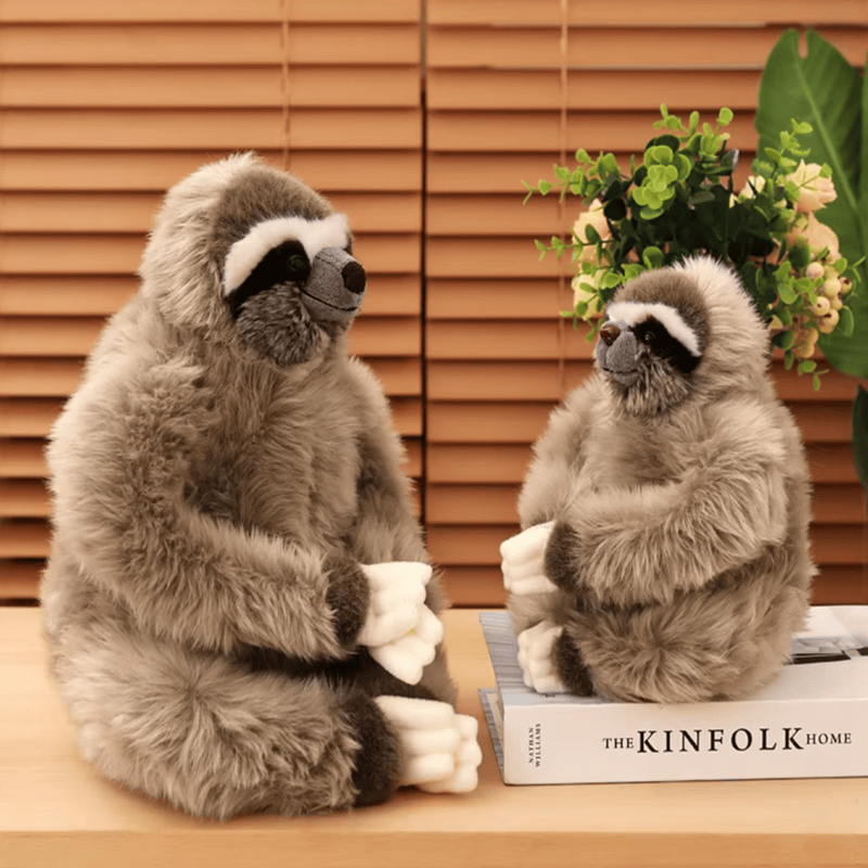 Deux peluches paresseux sur une table dont un sur un livre