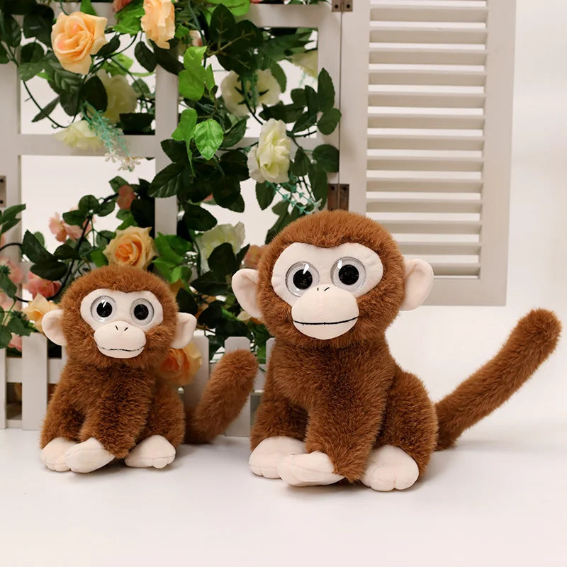 Deux peluches singes aux gros yeux assis devant une fenêtre avec des fleurs