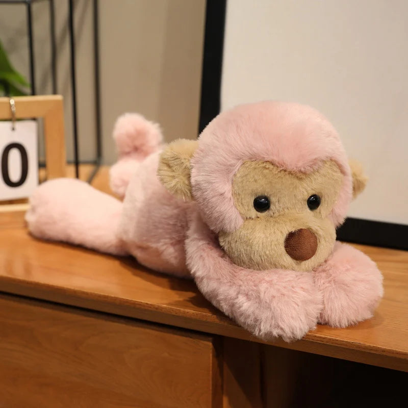 Peluche singe rose douce sur un meuble