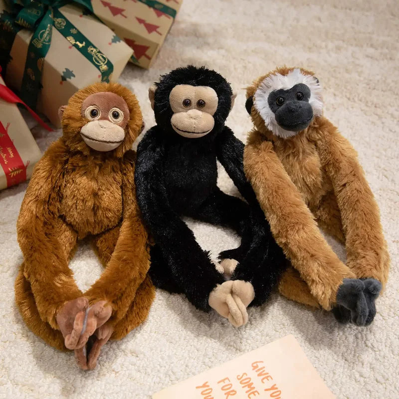 Trois peluches sur un tapis dont un orang-outan, un chimpanzé et un gibbon