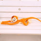 Peluche singe orange suspendu couché sur un banc