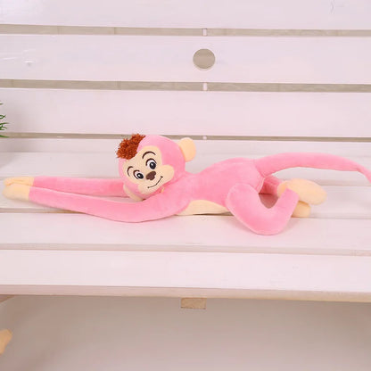 Peluche singe rose suspendu couché sur un banc