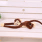 Peluche singe marron suspendu couché sur un banc