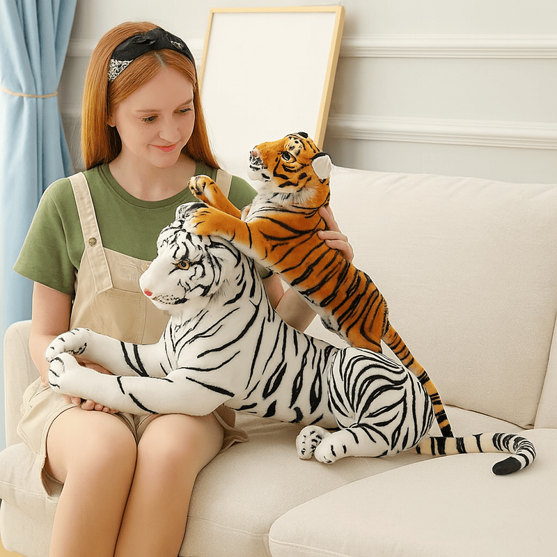 Deux peluches tigres allongés sur un canapé et sur les genoux d'une fille