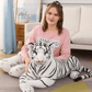 Peluche tigre allongé sur un tapis avec une fille avec son coude sur son dos 