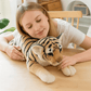 Peluche tigre beige sur une table avec une fille ayant la tête posée dessus