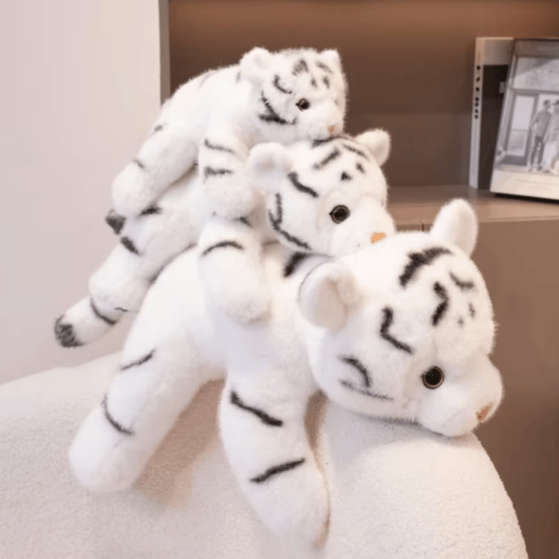 Trois peluches tigres blancs mignons sur une couverture