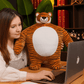 Peluche tigre super-héros sur une table avec une fille devant un macbook 